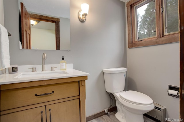 bathroom featuring hardwood / wood-style floors, vanity, toilet, and a baseboard heating unit