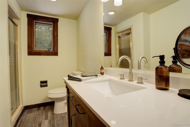 bathroom featuring vanity, hardwood / wood-style flooring, toilet, and a shower with door