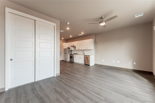 unfurnished living room featuring sink, ceiling fan, and light hardwood / wood-style flooring