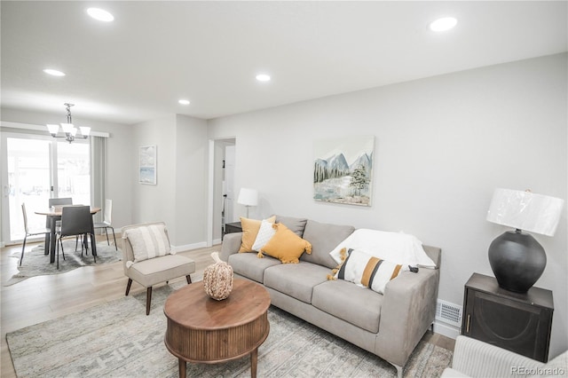 living room featuring an inviting chandelier and light wood-type flooring