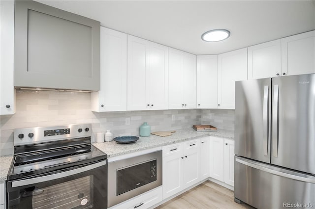 kitchen featuring light stone counters, stainless steel appliances, tasteful backsplash, and white cabinets