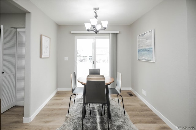 dining space with a notable chandelier and light hardwood / wood-style floors