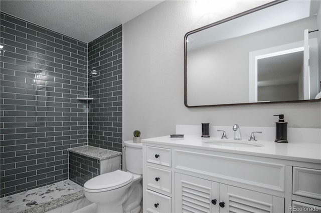 bathroom featuring vanity, a textured ceiling, toilet, and tiled shower