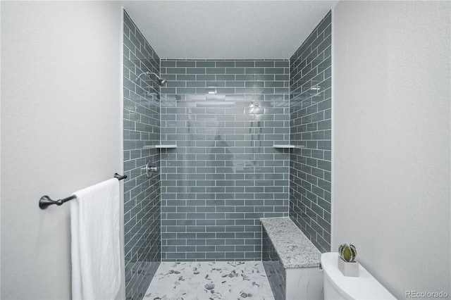 bathroom featuring tiled shower and toilet