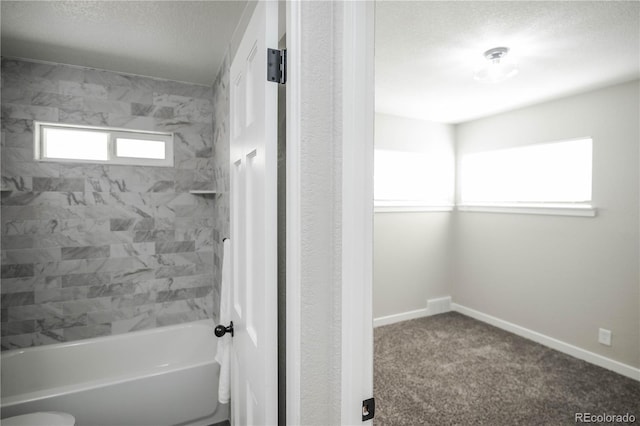 bathroom with tiled shower / bath, toilet, and a textured ceiling