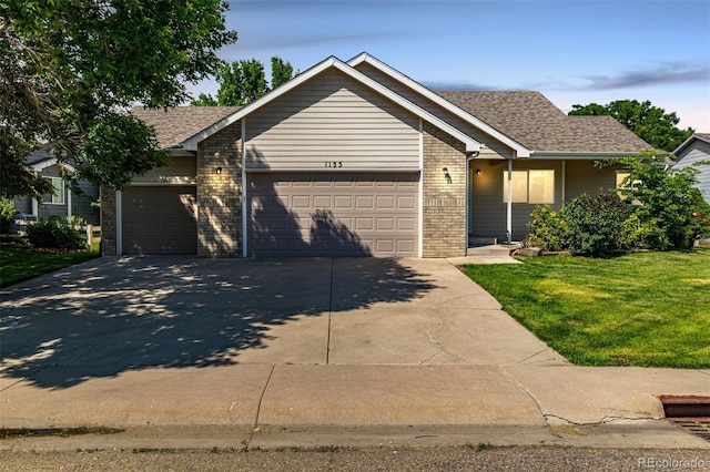 1155 Black Hawk Rd, Eaton, CO 80615 - ranch-style home featuring a garage, driveway, brick siding, a front lawn, and a shingled roof