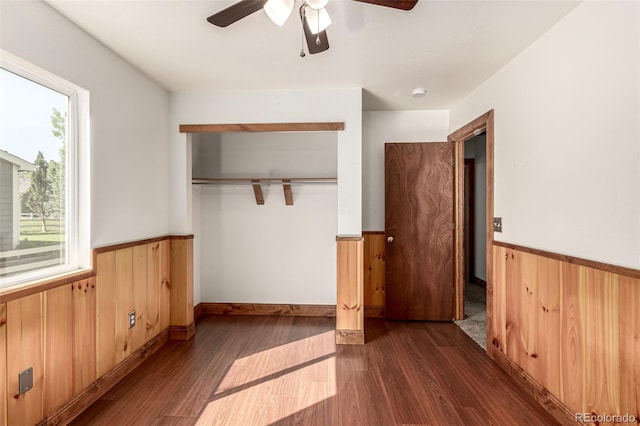 1155 Black Hawk Rd, Eaton, CO 80615 - unfurnished bedroom with wainscoting, wooden walls, wood finished floors, a closet, and a ceiling fan