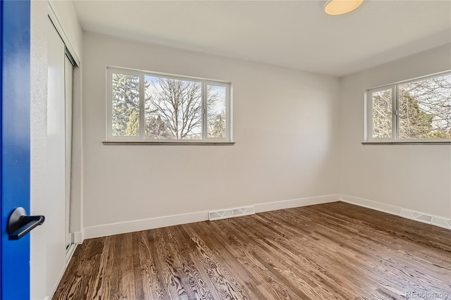 empty room with plenty of natural light and hardwood / wood-style floors