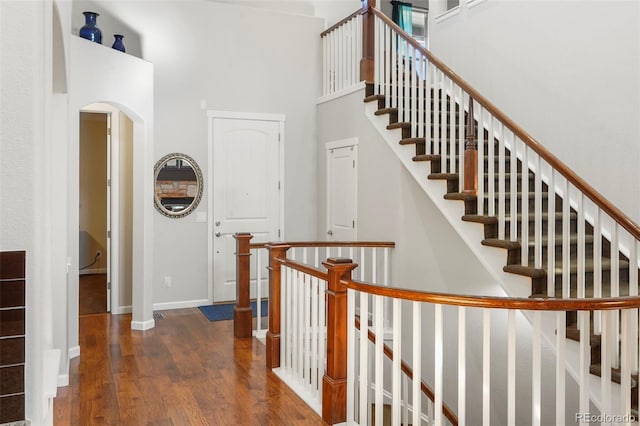 stairs with wood-type flooring and a towering ceiling