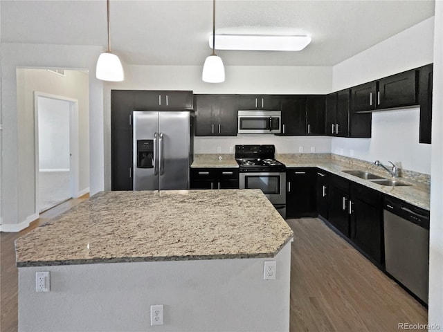 4100 Albion St Unit 523, Denver, CO 80216 - kitchen with appliances with stainless steel finishes, dark cabinetry, a center island, wood finished floors, and decorative light fixtures