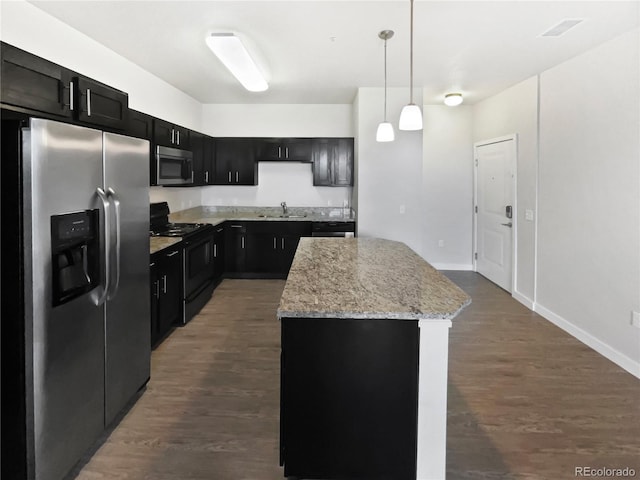 4100 Albion St Unit 523, Denver, CO 80216 - kitchen with stainless steel appliances, a center island, dark cabinets, and hanging light fixtures