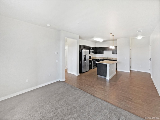 4100 Albion St Unit 523, Denver, CO 80216 - kitchen featuring appliances with stainless steel finishes, open floor plan, a center island, light countertops, and dark wood-style floors