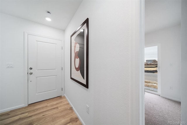 hall with light wood-style flooring and baseboards