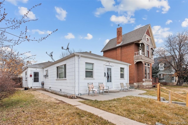 back of property featuring a balcony, a patio area, and a lawn