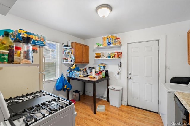 kitchen with light hardwood / wood-style flooring, white gas range, and washer / clothes dryer