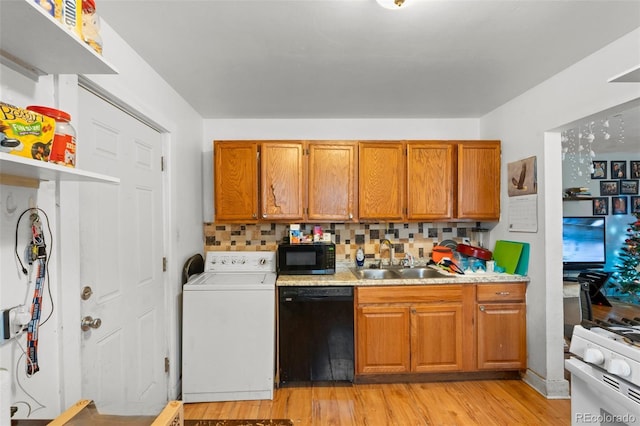 kitchen with washer / dryer, decorative backsplash, black appliances, light hardwood / wood-style flooring, and sink