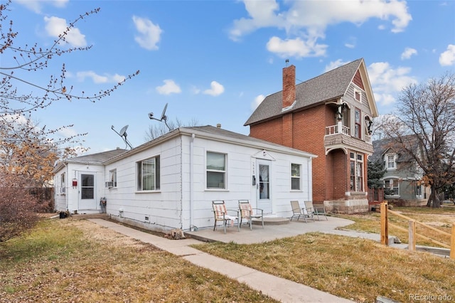 rear view of house with a patio, a lawn, and a chimney