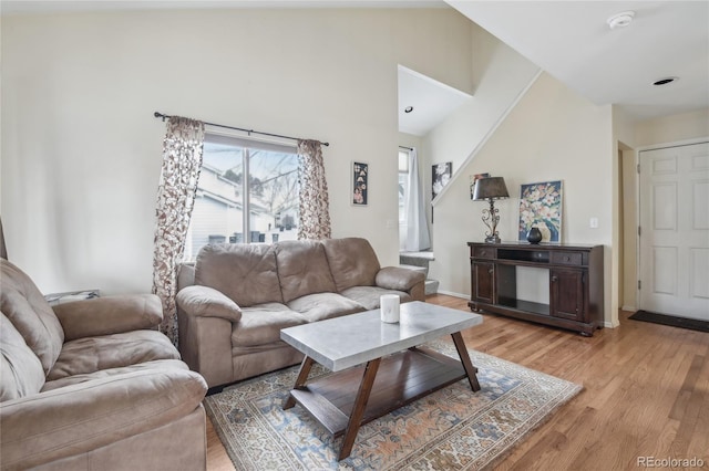 living room with high vaulted ceiling and light wood-type flooring