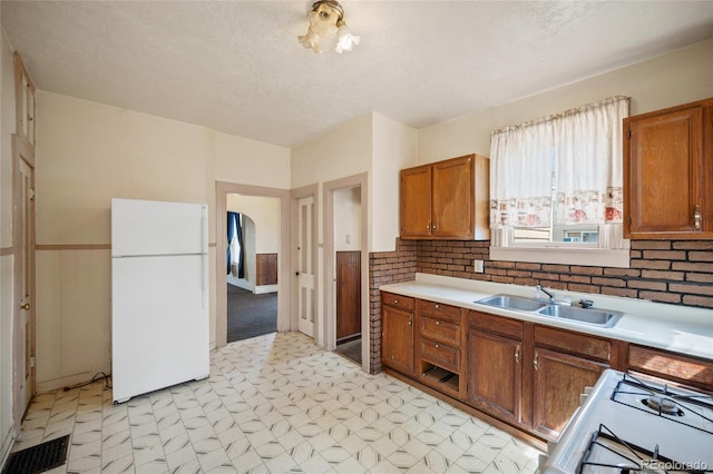 125 S Limit St, Colorado Springs, CO 80905 - kitchen with freestanding refrigerator, a sink, light flooring, gas range oven, and brown cabinetry