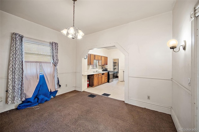 125 S Limit St, Colorado Springs, CO 80905 - unfurnished dining area with light carpet, a chandelier, baseboards, a sink, and arched walkways