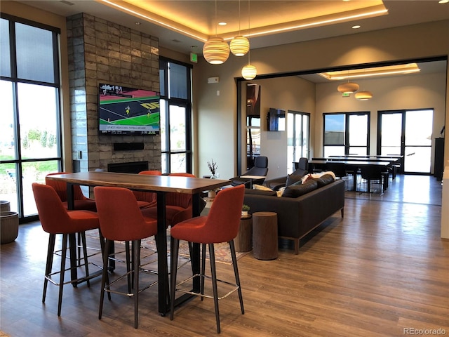 dining room featuring a fireplace, a raised ceiling, and wood finished floors