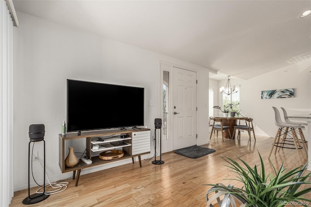 living room with lofted ceiling, a notable chandelier, and light hardwood / wood-style flooring