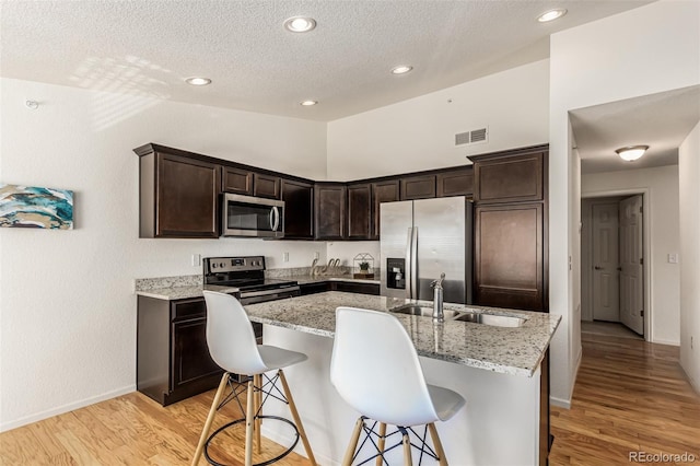 kitchen featuring a center island with sink, light wood-type flooring, sink, and stainless steel appliances