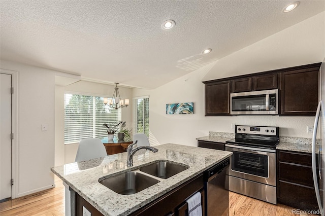 kitchen with light hardwood / wood-style floors, a kitchen island with sink, sink, stainless steel appliances, and lofted ceiling