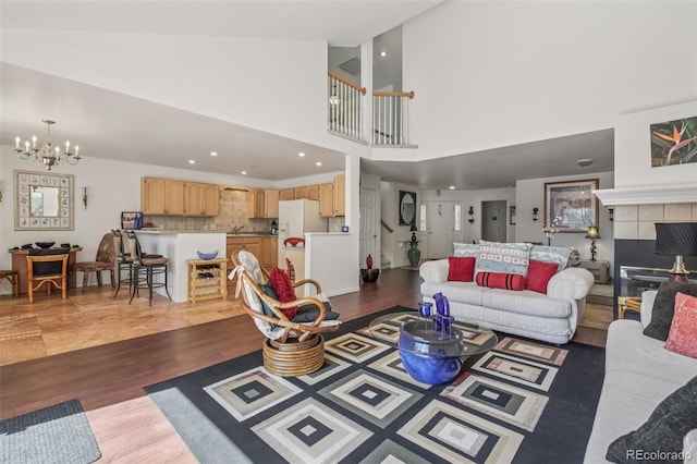 7664 S Ivanhoe Way, Centennial, CO 80112 - living area with a chandelier, light wood-style flooring, a tiled fireplace, recessed lighting, and a high ceiling