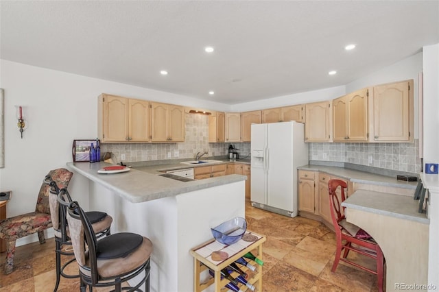 7664 S Ivanhoe Way, Centennial, CO 80112 - kitchen featuring white appliances, light brown cabinets, a peninsula, a breakfast bar, and tasteful backsplash