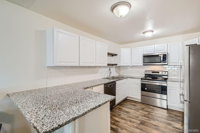 kitchen with white cabinetry, stainless steel appliances, dark hardwood / wood-style flooring, kitchen peninsula, and sink