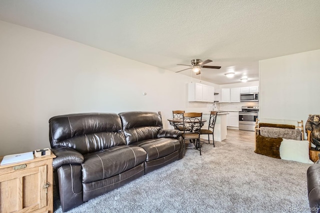 carpeted living room featuring a textured ceiling and ceiling fan