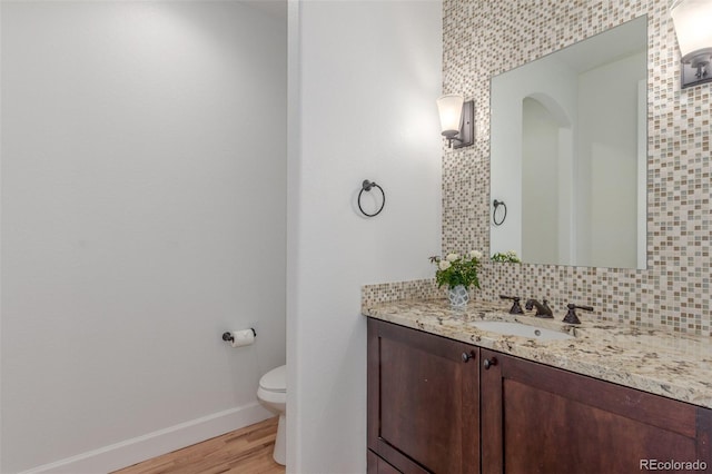 3322 W 26th Ave, Denver, CO 80211 - bathroom with vanity, toilet, baseboards, wood finished floors, and decorative backsplash