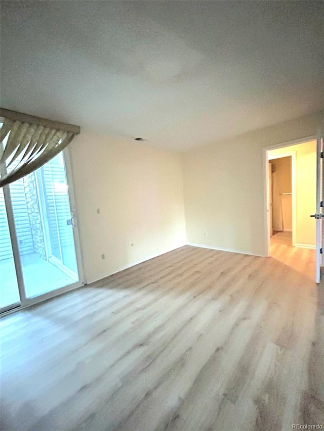 empty room with light hardwood / wood-style flooring and a textured ceiling