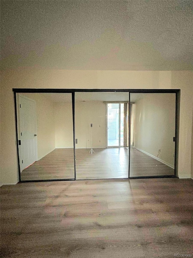 unfurnished bedroom featuring hardwood / wood-style floors, a textured ceiling, and a closet