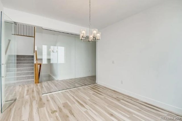 empty room with an inviting chandelier and light wood-type flooring