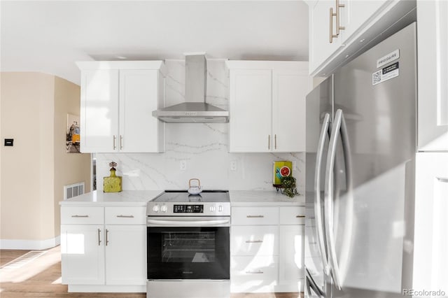 kitchen with white cabinetry, wall chimney range hood, and appliances with stainless steel finishes