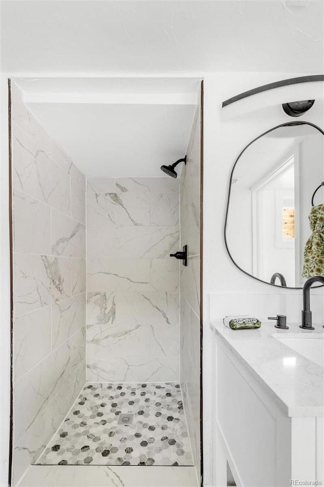 bathroom with vanity and a tile shower