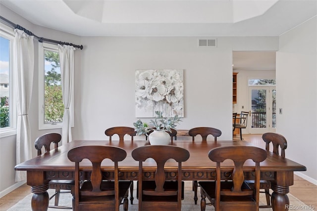 dining area featuring baseboards, visible vents, light wood-style floors, and a healthy amount of sunlight