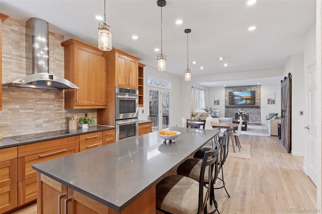 kitchen with wall chimney exhaust hood, dark countertops, backsplash, stainless steel double oven, and black electric stovetop