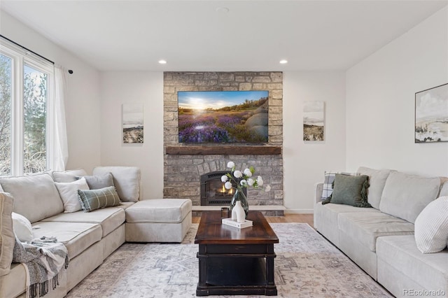 living area with light wood-style floors, a stone fireplace, and recessed lighting