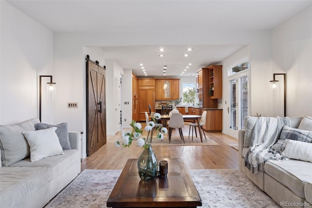living room featuring light wood finished floors, baseboards, recessed lighting, and a barn door
