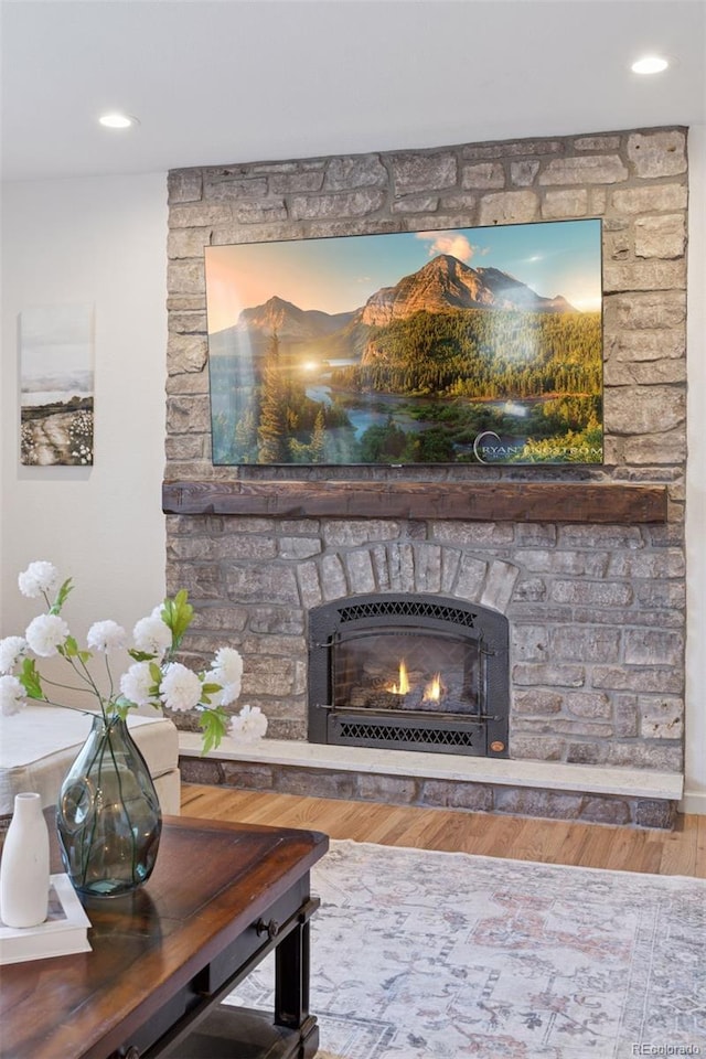 interior details featuring wood finished floors, a stone fireplace, and recessed lighting
