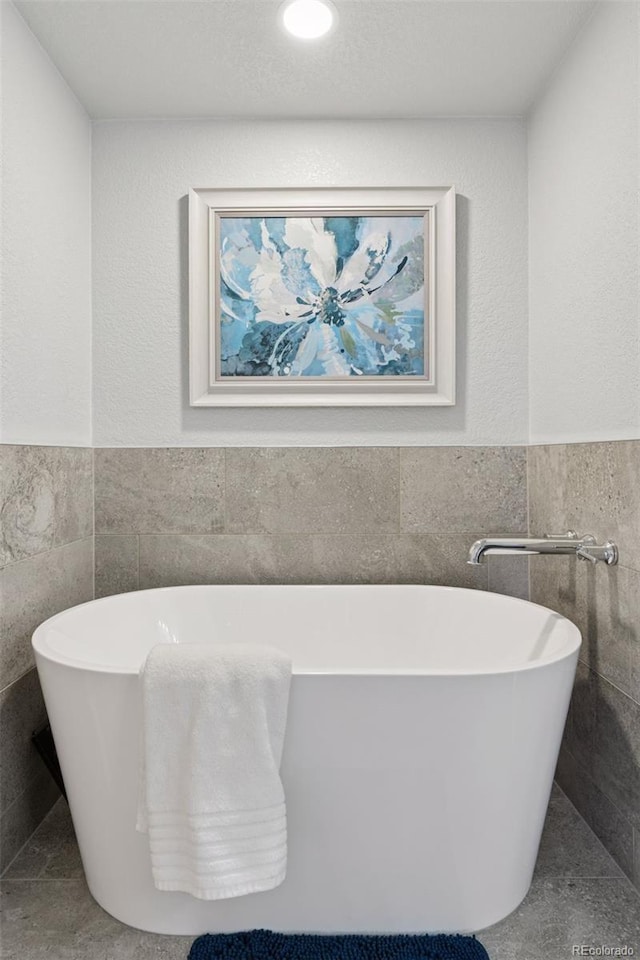 full bath with tile walls, a wainscoted wall, and a freestanding tub