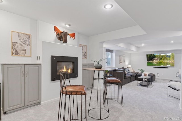 living room with light colored carpet, baseboards, a glass covered fireplace, and recessed lighting
