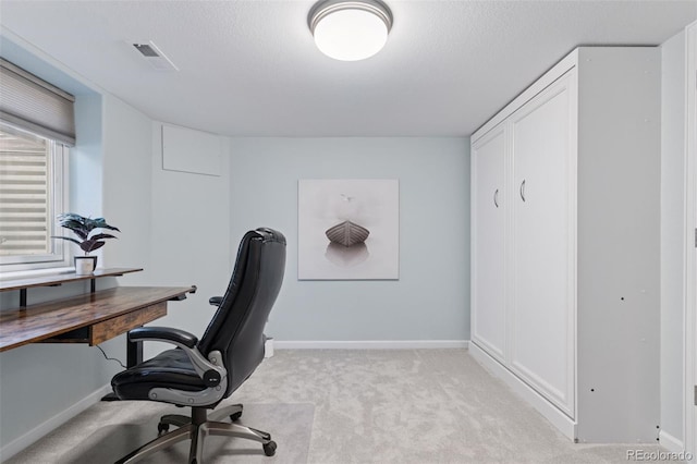 office area featuring a textured ceiling, visible vents, baseboards, and light carpet