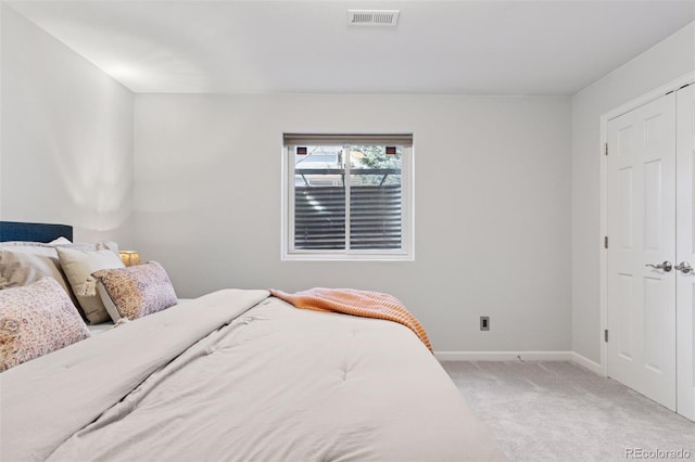 bedroom with baseboards, visible vents, a closet, and light colored carpet