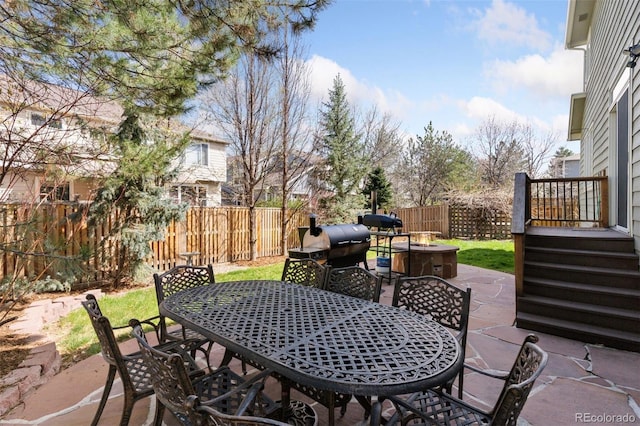 view of patio / terrace with a fenced backyard, an outdoor fire pit, area for grilling, and outdoor dining space