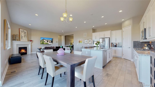 dining space with light wood-type flooring, sink, and a notable chandelier