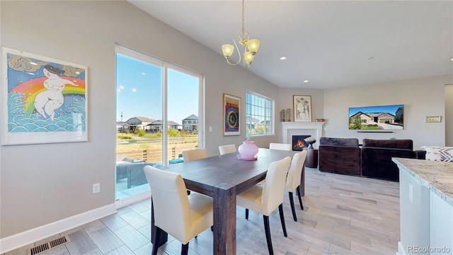 dining space featuring a notable chandelier, light wood-type flooring, and a healthy amount of sunlight